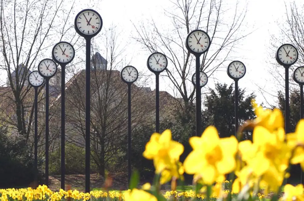 Deze afbeelding toont 24 stationsklokken in de Volksgarten in Düsseldorf, vlakbij het gelijknamige station. Dit is een kunstwerk van kunstenaar Klaus Rinke dat de vergankelijkheid en tijd symboliseert. Foto: Oege Kleijne.