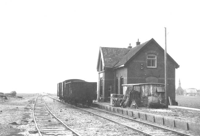 Vrouwenparochie aan de westtak (Stiens - Tzummarum) op 4 april 1958 met verschillende goederenwagens. Op veel van dergelijke stationnetjes stonden in de jaren vijftig 'bakken' van oude goederenwagons die als opslagruimte werden gebruikt. Foto: Roef Ankersmit.
