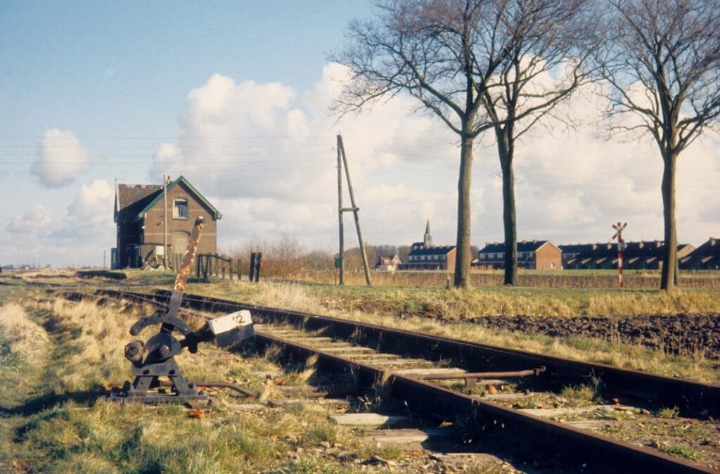 Het verlaten spoor bij Vrouwenparochie met het haltegebouw en de restanten van het perron, maart 1973. Foto: Wietse Hoekstra.