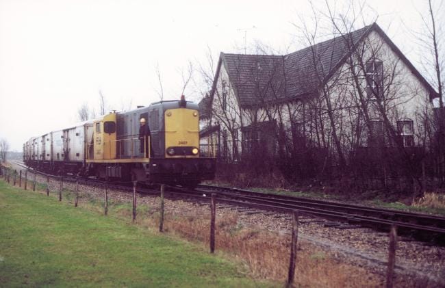 Diesellocomotief 2407 komt koelwagens brengen te Stiens (rechts het stationsgebouw) en rijdt leeg terug op 5 januari 1988. Foto: Roelof Hamoen.