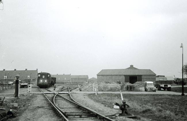 Diesellocomotief 2420 op het emplacement van Sint-Jacobi Parochie, gezien in de richting van Stiens. Foto: Kees van de Meene, 4 april 1958.