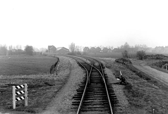 Blik op het emplacement van het station Ternaard vanaf de locomotief gezien in de richting Stiens. Het links leidende spoor was het doorgaande. 4 april 1958. Foto: Kees van de Meene.