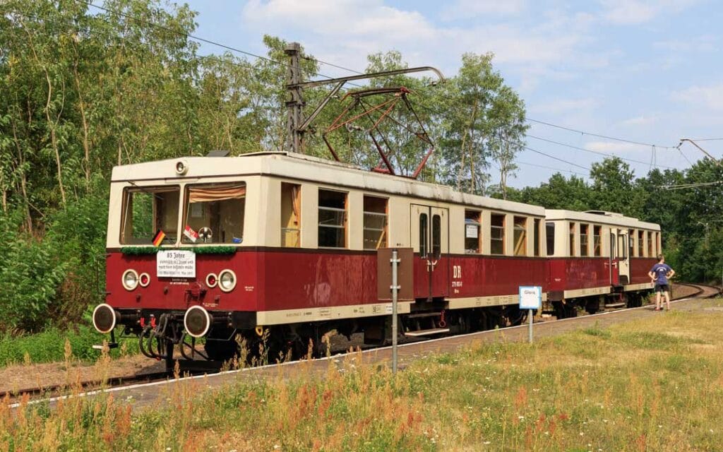 Deze foto toont een trein van de Buckower Kleinbahn op het aparte perron van het station Müncheberg (Mark) op 15 augustus 2015, tijdens het 85-jarig jubileum van de elektrische treinen op dit traject. Foto: A.Savin (Wikipedia).